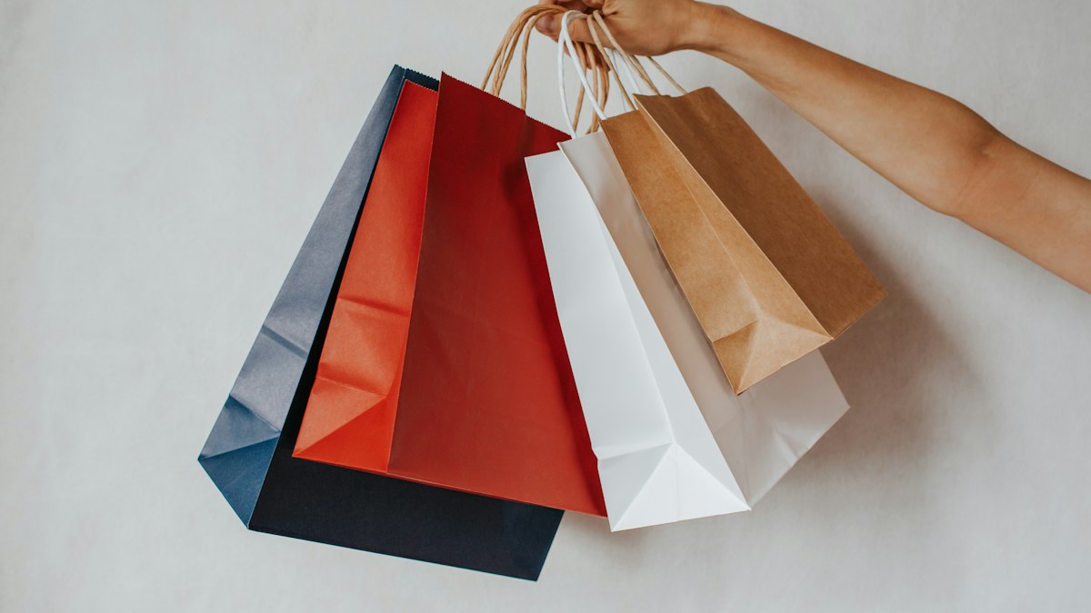 Mano sosteniendo bolsas de compras de colores